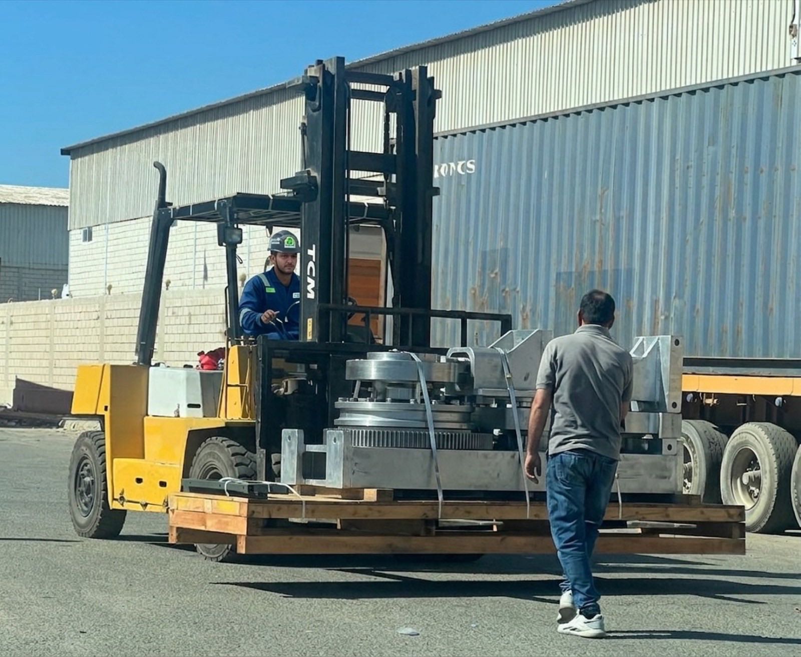 A Specialized Networks operator loading machinery onto a flatbed trailer with a forklift